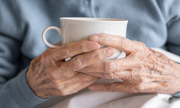 Close-up of an older person's hands holding a tea cup