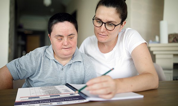 A nurse sitting at a table with a person with learning disabilities and epilepsy going through the Clive Treacey Safety Checklist
