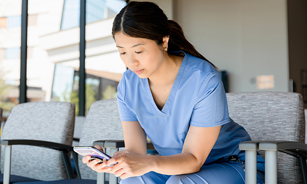 A young female care worker sitting on a chair and looking at her phone