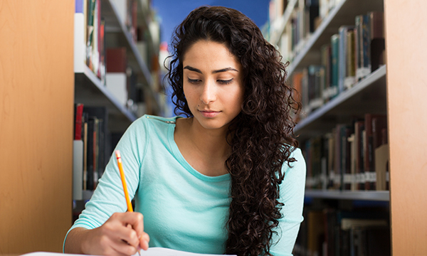  Nursing student makes notes in a library in preparation for submitting a written assignment