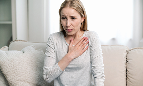 Nurses with long-COVID: a woman clutches her chest due to shortness of breath, a common symptom of long-COVID