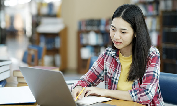 Nursing assessment: a young woman working on a laptop in a library