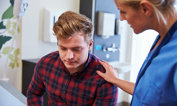 A nurse talks to a young man who looks distressed
