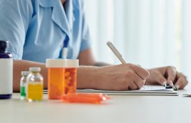 Medicines arranged on a table where a nurse is making notes