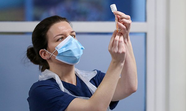 A nurse prepares a vial of a coronavirus vaccine