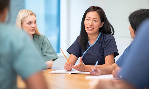 Senior nurse role profiles: ward manager in team meeting. Nurses in bands 7,8 and 9 have been undervalued in roles review, RCN claims