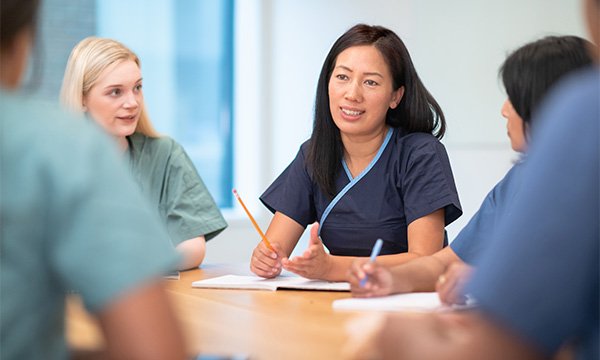 Nurses listen to the senior nurse in a team meeting