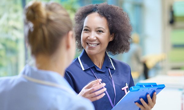 A smiling nurse leader in conversation with a team member