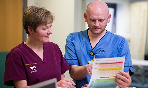 Nurse and doctor confer while reading sepsis tool paperwork
