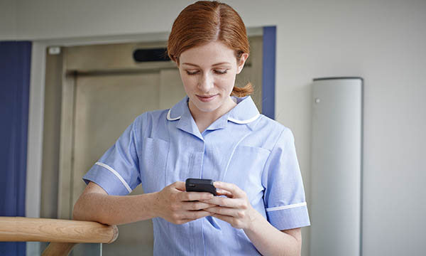 A nurse accessing social media via a smart phone