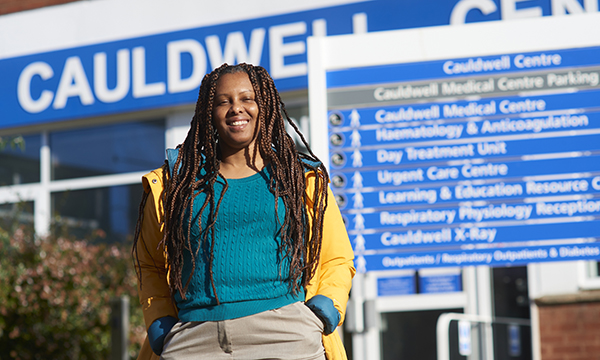 A picture of patient Joyce Tucker, smiling and looking relaxed with one hand in her pocket standing in front of Cauldwell Medical Centre, where she was part of the care improvement team set up by RCN Nurse of the Year 2023 Julie Roye