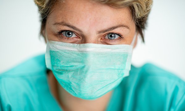 Nurse wearing a face mask – COVID-19 face coverings pose communication challenges for healthcare staff and people who are deaf or have dementia