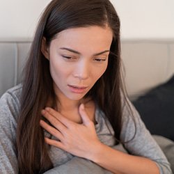 A woman holding her chest, due to shortness of breath