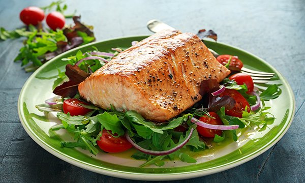 Picture shows a poached salmon fillet with vegetables. Oily fish are a rich source of vitamin D