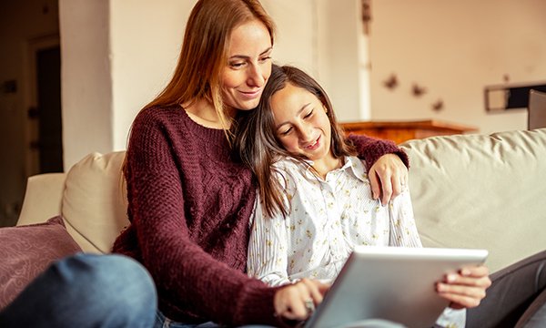Picture shows mother working with child on tablet computer.
