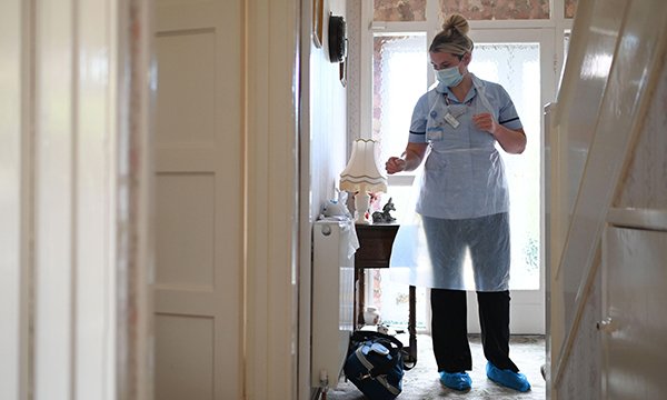 A nurse in PPE in the hallway of a patient's home