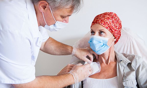 Masked patient prepares to receive cancer treatment