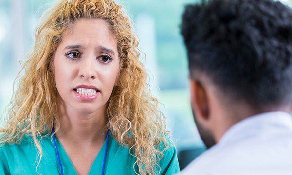 Woman dressed in scrubs speaking to another person in a counselling session