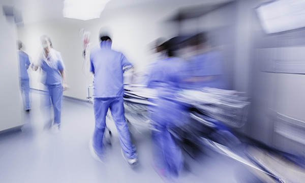 Image showing nursing team in hospital moving a patient trolley, blurred to give impression of moving quickly