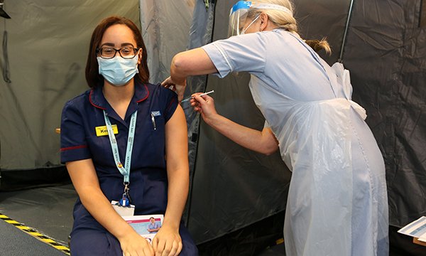 Picture shows nurse Kerry Holden receiving the vaccination from Lorna Harold.