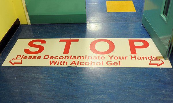 Sign on the floor in a hospital reminding people to use alcohol hand gel