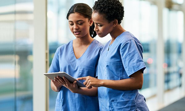 Picture shows two women dressed in smart scrubs