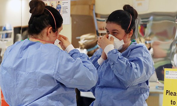 Nurse dons PPE, which will still be provided free in England