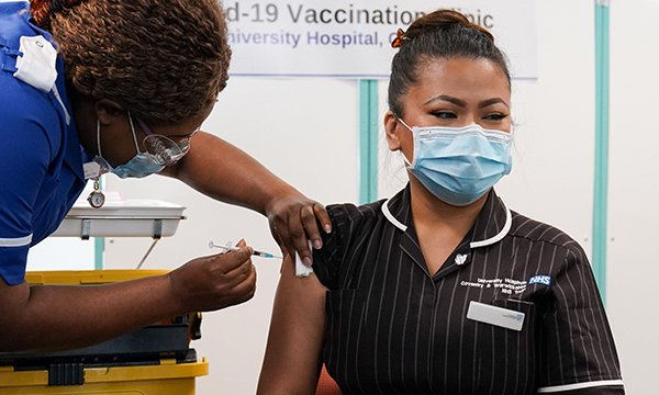 nurse receives a coronavirus vaccination from NHS colleague