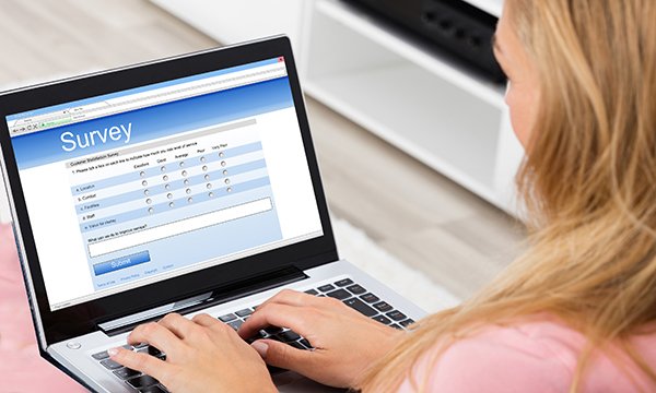 Picture shows a woman looking at a computer screen and completing a survey