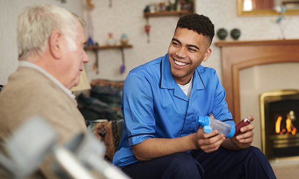 Community nurse who is a man chats to patient during a home visit
