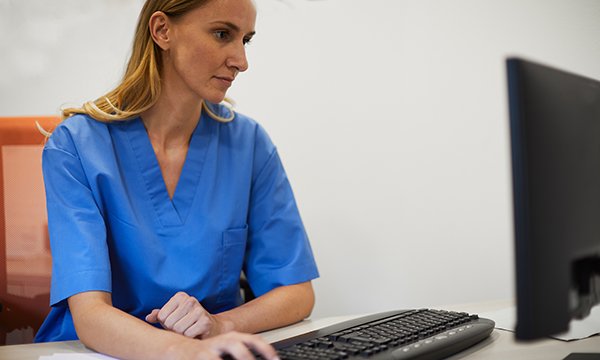 Photo of a nurse using a computer at a desk: safety concerns prompted by staffing issues are being ignored and nurses dissuaded from filing reports