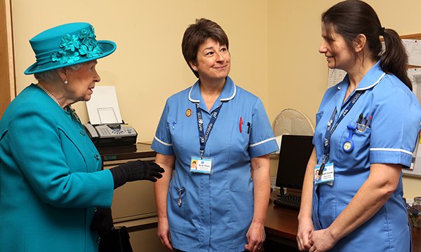 Queen Elizabeth II meets nurses Sarah Wallis and Daniela Reynolds during a visit to The Norfolk Hospice at Hillington in 2016