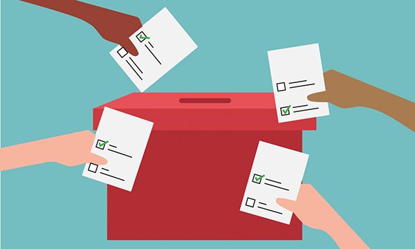 Picture of four hands putting voting slips in a red ballot box