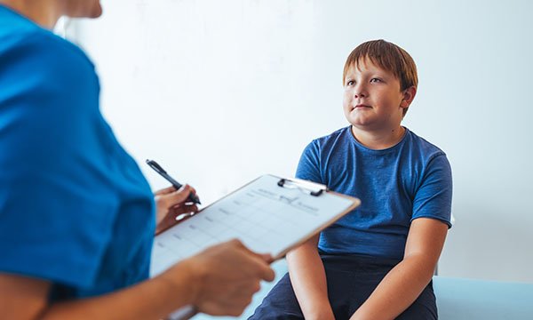 Nurse with a clipboard talks to a young patient