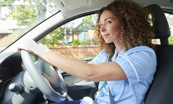 Nurse sitting at the steering wheel of a car