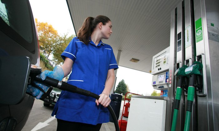 Nurse filling her car at a petrol pump 