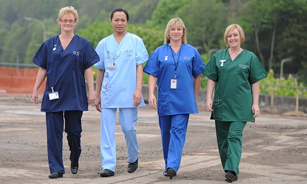 Four people walking towards the camera model nurses’ uniforms in Wales