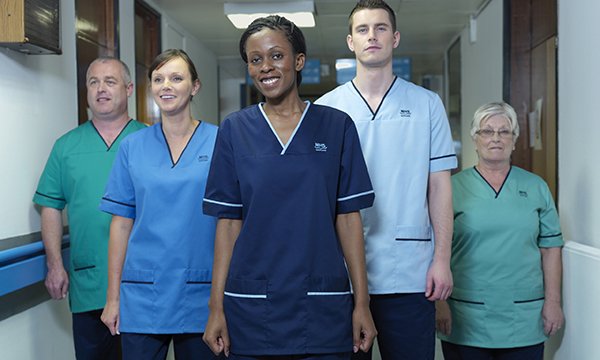 Five people in a hospital corridor model nurses’ uniforms in Scotland