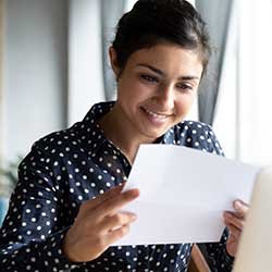 A woman smiling as she reads a job offer in a letter