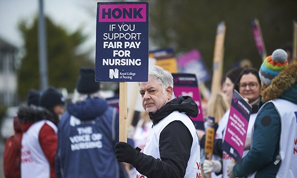  Nurses on the picket line during recent strike action, with a man at the front holding a sign that reads ‘Honk is you support fair pay for nursing’