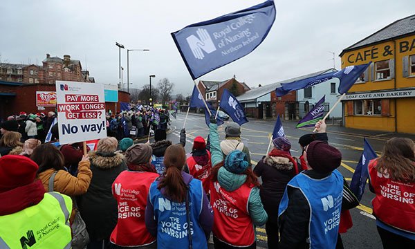 Photo of striking nurses waving flags and holding placards outside the Royal Victoria Hospital in Belfast 