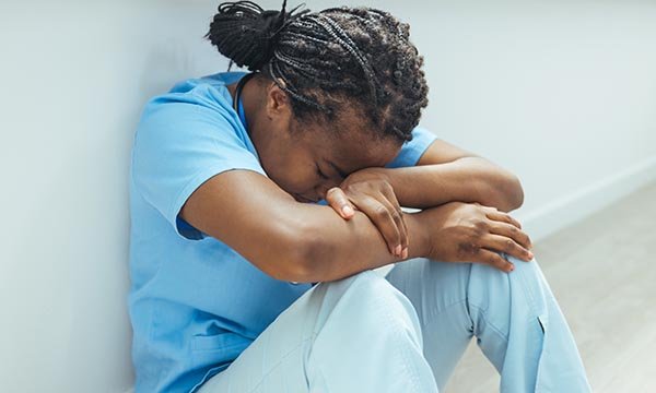 Photo of black nurse looking depressed, illustrating story about racial harassment at work