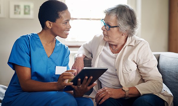 Nurse assessing cognition of an older woman using a digital tablet in a care home