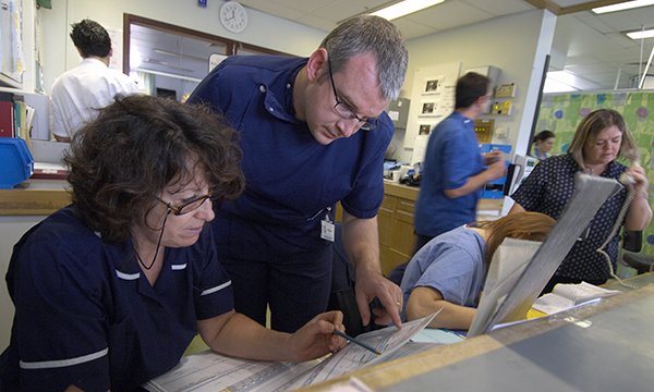 Nurses check paperwork together, one explaining it to the other
