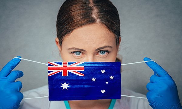 Nurse part shields her face with mask bearing image of Australian flag