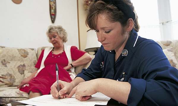 A nurse fills in some paperwork during a home visit for wound care