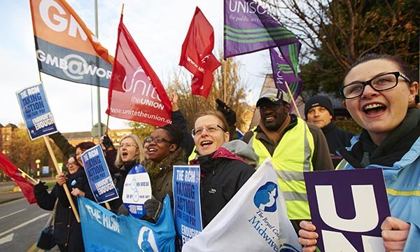 Striking nurses on a picket line holding banners