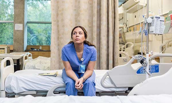 Photo of a nursing student sitting on a hospital bed looking unhappy