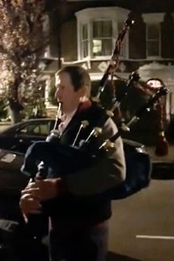 Picture of Alastair Campbell playing bagpipes for his neighbour’s nurse daughter during the pandemic