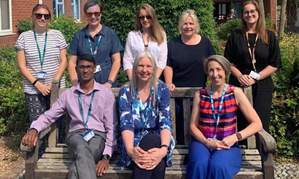 Members of the Care Home Memory Assessment Service team, winners of the Nursing Older People award at the RCN Nursing Awards 2023, sitting and standing in a garden outside their workplace
